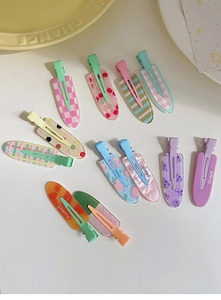Flat lay of colorful candy-colored hair clips with fruit patterns like peach and cherry