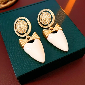 Macro detail of vintage gold bow earrings with crystal heart pendants on green box