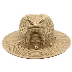 Close-up of beige straw Fedora with suede band and golden metal beads decoration