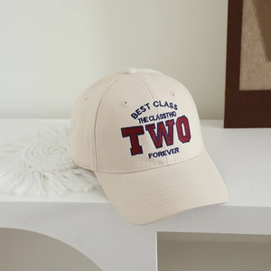 Close-up of beige kids baseball cap featuring blue and red 3D letter embroidery detail