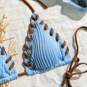 Detail of light blue ribbed bikini top featuring silver eyelets and brown criss-cross ties