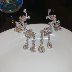 Detail shot of silver floral tassel earrings with sparkling rhinestones on a white tray