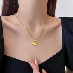 Minimalist gold ginkgo leaf pendant necklace on model with titanium steel snake chain