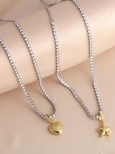 Close-up of gold plated heart and star pendants on sparkling tennis chains over silk