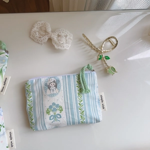 Detailed close-up of a blue striped floral cotton pouch with girl portrait illustration