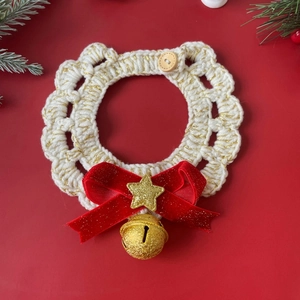 Close-up of handmade crochet Christmas pet collar with gold bell and star on red background