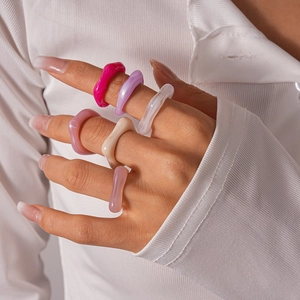 Détail de bagues en résine colorée aux designs irréguliers portées par un mannequin