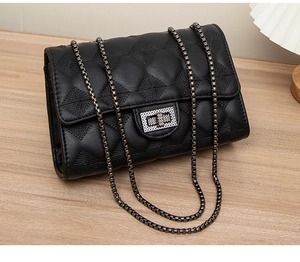 Close-up of black quilted chain bag with metal lock detail on wooden surface