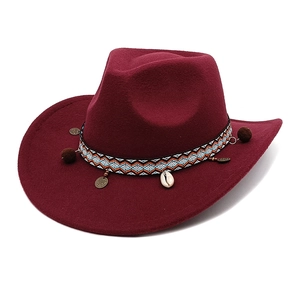 Detail of burgundy felt fedora with ethnic woven band, pom-poms, and shell charms