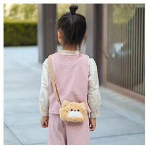 Detail of yellow plush cat crossbody bag with 3D ears and embroidery on a child