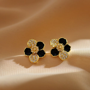 Close-up of elegant gold flower earrings with black enamel and micro-pave crystals