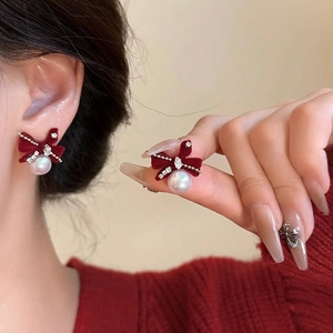 Detail view of red velvet bow earrings with rhinestones and hanging pearl drop
