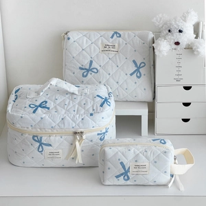Three-piece quilted white cosmetic bag set with blue polka dots and bow patterns
