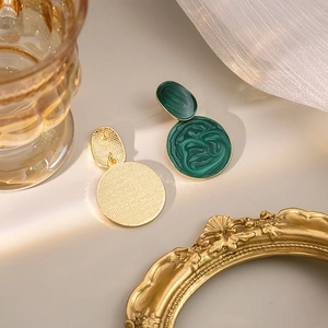 Close-up of green marble texture enamel earrings with vintage gold metal details
