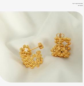 Macro view of 18K gold plated beaded mesh C-shaped hollow stud earrings on silk
