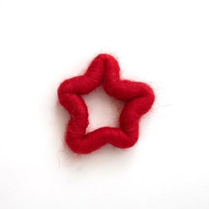 Handmade red wool felt star Christmas ornament with soft fiber texture on white background