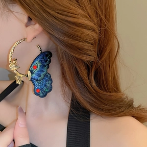 Vintage gold hoop earrings with blue embroidered butterfly and colorful beads on model