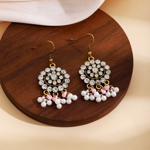 Detail of bohemian gold earrings with white rhinestones and dangling bead tassels