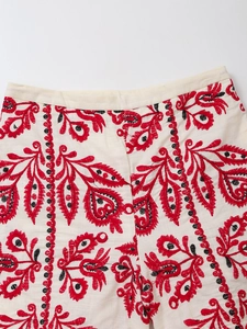 Détail de broderie rouge et noire sur short en lin blanc avec texture naturelle