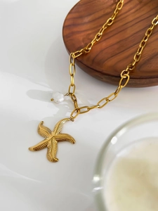 Détail d'un collier en acier inoxydable doré 18K avec pendentif étoile et perle