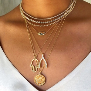 Détail de colliers multicouches plaqués or 18 carats avec pendentifs Hamsa et Œil de Mauvais