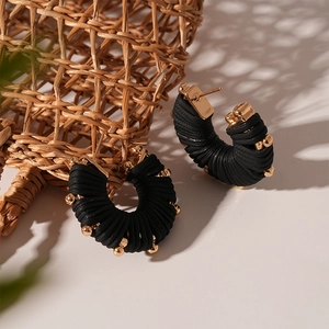 Macro detail of U-shape striped earrings with black leather wrap and gold beads