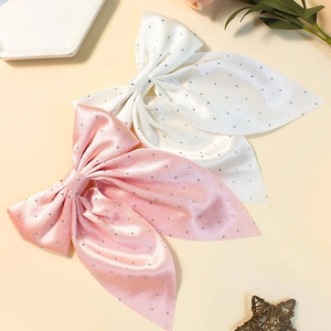 Detail showing pink and white satin bow hair clips with sparkling rhinestone accents