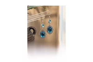 Detail shot of vintage lake blue resin drop earrings with ornate silver lace alloy frame