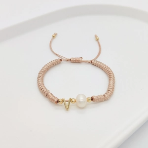 Detail of hand-woven pink rope bracelet featuring letter V charm and natural pearl