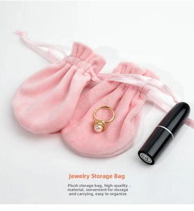 Close-up of pink plush drawstring jewelry bag with golden pearl ring on white background