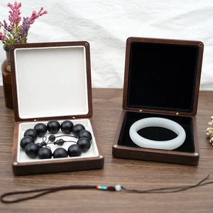 Detailed view of wood jewelry boxes with black bead bracelet and white jade bangle