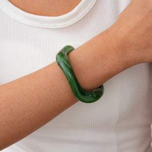 Detail of green acrylic twisted bangle with jade-like texture on a model wrist