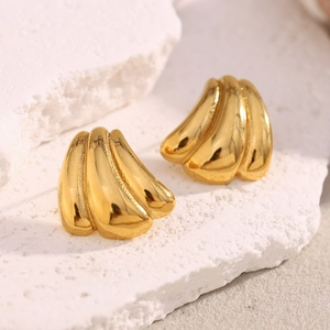 Macro detail of gold-plated pumpkin shape earring on a white textured stone background