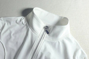 Close-up of white slim fit top featuring a metal zipper and stand collar detail