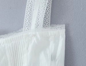 Detailed macro view of white lace straps and pleated fabric texture on a camisole top