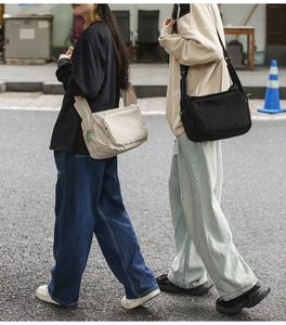 Lifestyle shot of large nylon messenger bags in beige and black with adjustable straps