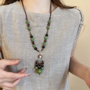 Detail of vintage necklace featuring coconut shell beads and engraved silver hollow pendant