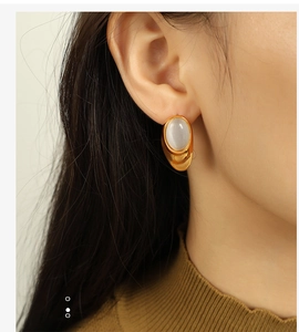 Detailed close-up of 18k gold-plated stud earring with oval white opal on a model