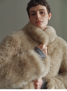 Detail of oat beige curly lamb fur texture and warm minimalist faux fox fur vest finish