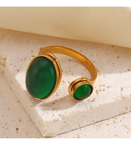 Close-up of gold stainless steel ring with two green stones on a textured stone base