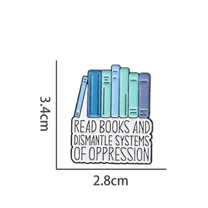 Enamel book brooch with Read Books and Dismantle Systems of Oppression quote