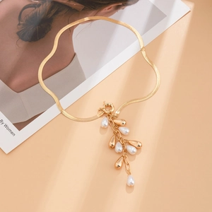 Detail view of golden flat snake chain necklace with pearl and metal tassel pendants