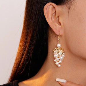 Detailed close-up of Baroque pearl grape clusters with golden leaf drop earrings on model