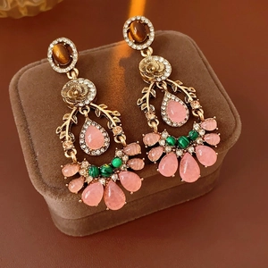 Detail of vintage gold earrings with pink gemstones and colorful crystal rhinestones