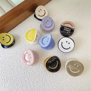 Mini acetate smiley face hair clips in various colors scattered on a white surface