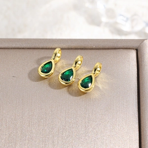 Detailed macro view of 18k gold plated teardrop pendants with green zircon stones