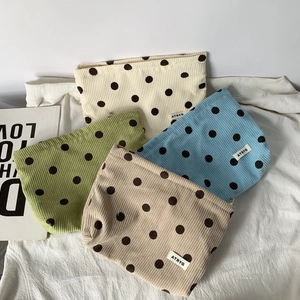 Detail of colorful corduroy polka dot bags stacked on a soft fabric background