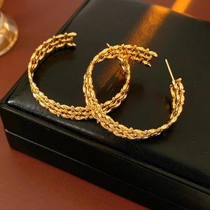 Detailed view of textured gold wide-surface hollow C-hoop earrings on a black jewelry box