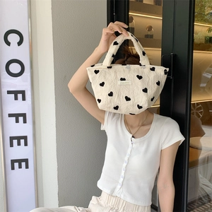 Close-up of beige textured canvas tote bag with black heart patterns in street style
