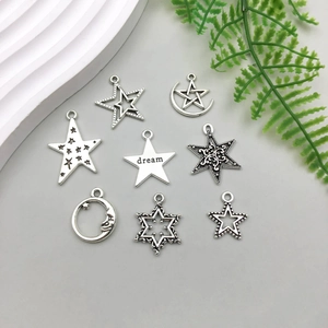 Flat lay of 8 silver star and moon pendants including a dream engraved star charm